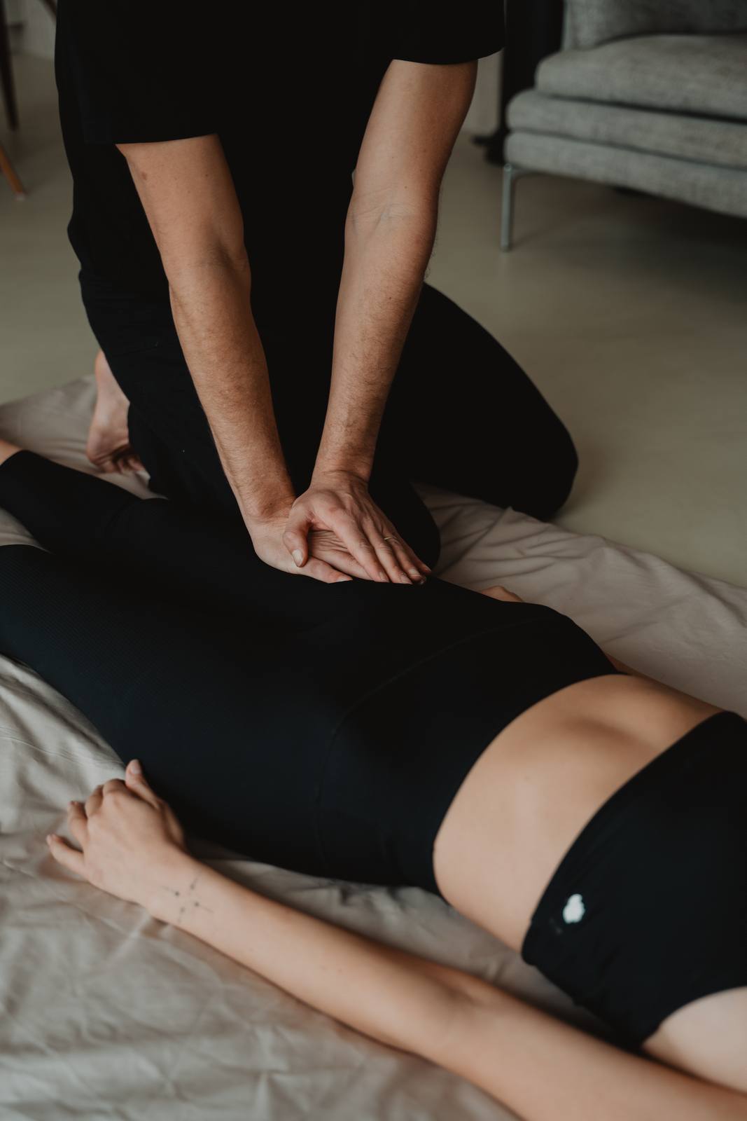 Pression des paumes sur la cuisse pendant un massage thaï, habillé, au sol