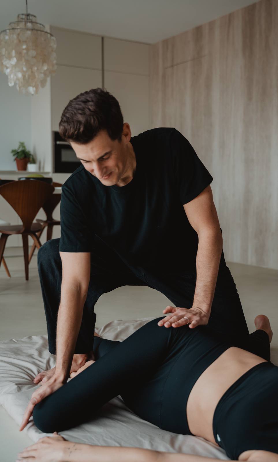 Julien Jacquier appuie avec les paumes sur les jambes d'une personne allongée sur le futon